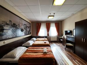 a hotel room with three beds and a desk at Hotel Mieszko in Rzeszów