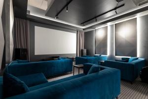 a waiting room with blue couches and a screen at Tempus Te Premium Duo Lofts Tartu - private cinema, gym and terrace in Tartu