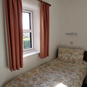 ein kleines Schlafzimmer mit einem Bett und einem Fenster in der Unterkunft Louisburgh Cottages in Louisburgh