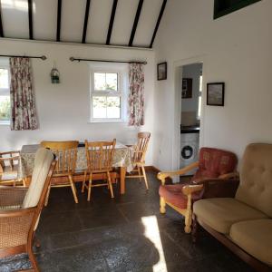 - un salon avec une table et des chaises dans l'établissement Louisburgh Cottages, à Louisburgh