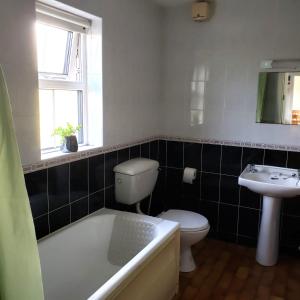 La salle de bains est pourvue d'une baignoire, de toilettes et d'un lavabo. dans l'établissement Louisburgh Cottages, à Louisburgh