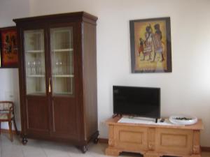 ein Wohnzimmer mit einem TV und einem Holzschrank in der Unterkunft Casa Del Sole in Gavardo