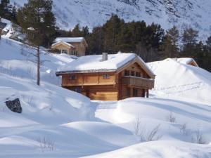 uma cabana de madeira na neve com telhados cobertos de neve em Skibyen Jons Hytte em Skoro