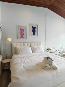 a bedroom with a large white bed with two pictures on the wall at Mr Black & Ms White -Self Check in accommodation in Pom Prap