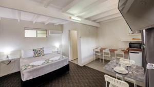 1 dormitorio con 1 cama y cocina con mesa en Oasis Motel, en Peak Hill