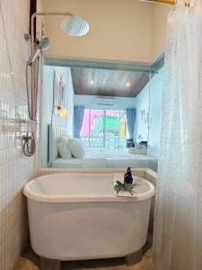 a bathroom with a tub with a bed in the background at Mr Black & Ms White -Self Check in accommodation in Pom Prap +32 photos
