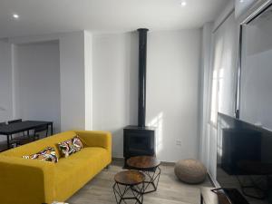 a living room with a yellow couch and a fireplace at El Refugio in Zahara de la Sierra