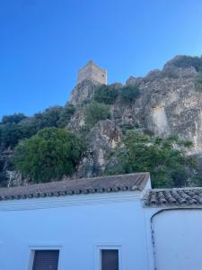 un castillo en la cima de una montaña detrás de un edificio en El Refugio en Zahara de la Sierra