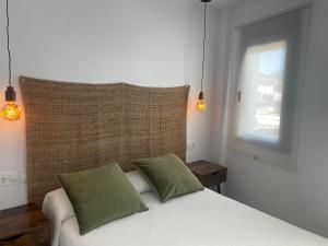 um quarto com uma cama branca e 2 almofadas verdes em El Refugio em Zahara de la Sierra