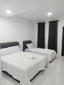 two beds in a white room with black curtains at Afeeya The Roomstay in Kuala Terengganu
