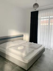 Cama blanca en habitación con ventana en BB Residence en Arad