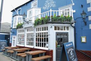 a blue building with tables and benches in front of it at Hampton Court Snug Sleeps 6 - 5min Walk to Palace and Train in East Molesey