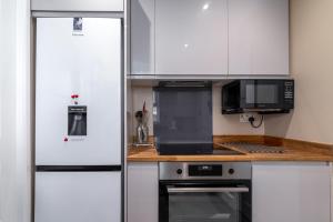 uma cozinha com armários brancos e um frigorífico em Central London 1 BR Apt in Vauxhall near Big Ben em Londres