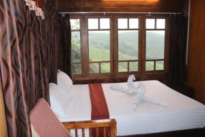 a bedroom with a bed with two white birds on it at spice garden Resorts munnar in Anachal
