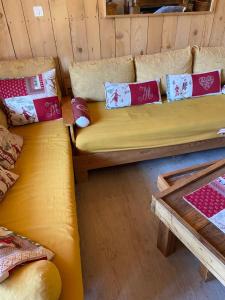 a yellow couch sitting in a room with pillows at BEL APPARTEMENT MONTAGNE AVEC VUE in Orcières