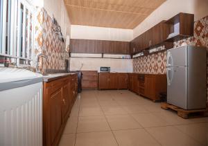 een keuken met houten kasten en een witte koelkast bij Sunset 4 bedroom Family Villa in Kigali