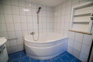 La salle de bains est pourvue d'une baignoire blanche et de carrelage blanc. dans l'établissement Holiday Home Aleks, à Lendava