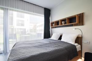 a bedroom with a bed and a large window at Apartament Royal Solny Resort z aneksem kuchennym w hotelu z krytym basenem, sauną i usługami SPA in Kołobrzeg