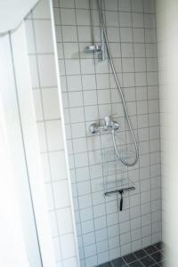 een douche met een slang in een wit betegelde badkamer bij Charmante la petite maison in Potsdam