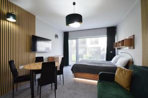 a bedroom with a bed and a table and a couch at Apartament Royal Solny Resort z aneksem kuchennym w hotelu z krytym basenem, sauną i usługami SPA in Kołobrzeg