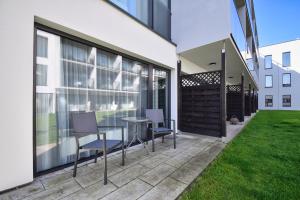 a patio with chairs and a table in front of a building at Apartament Royal Solny Resort z aneksem, klimatyzacją i konsolą PS4 w hotelu z krytym basenem, sauną i SPA in Kołobrzeg