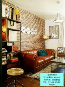 a living room with a brown leather couch and a brick wall at Les Appartements de Champagne in Reims