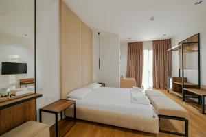 um quarto com uma grande cama branca e uma televisão em Hotel Central em Vlorë