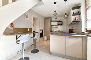 a kitchen with white cabinets and a bar with stools at Jaennette in Ribeauvillé