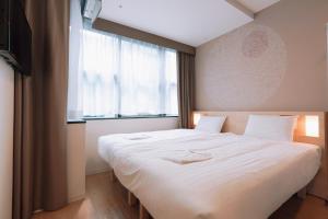 a bedroom with a large white bed with a window at Park Central Sakura Hotel in Osaka