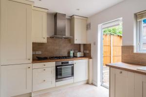Una cocina con gabinetes blancos y un horno de estufa. en Luxurious 4-Bed Holiday Retreat, en Finchley