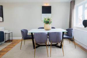 una mesa de comedor con sillas moradas y un jarrón con flores en Luxurious 4-Bed Holiday Retreat, en Finchley 13 fotos más