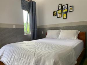 - une chambre dotée d'un lit blanc avec des photos sur le mur dans l'établissement Khách Sạn An Bình, à Phước Lộc Xã