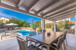 eine Terrasse mit Tisch und Stühlen und ein Swimmingpool in der Unterkunft Villa Zora in Rasopasno