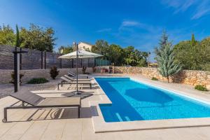 ein Swimmingpool mit Liegestühlen und Sonnenschirm in der Unterkunft Villa Zora in Rasopasno