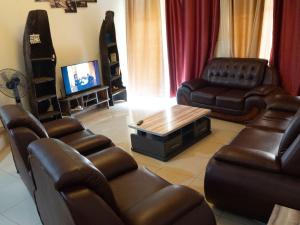 een woonkamer met lederen meubels en een televisie bij Sunset 4 bedroom Family Villa in Kigali