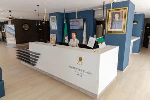 a woman is sitting at a counter in a store at BOUMERDES PLAZA Hôtel & Spa in Boumerdes