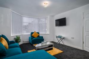 a living room with two blue chairs and a tv at Borrowdale Brook in Moortown