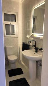ein Badezimmer mit einem Waschbecken, einem WC und einem Spiegel in der Unterkunft Sweet Apartment Madinaty in Madinaty