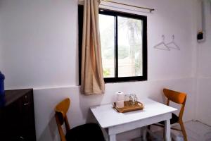 uma mesa branca e cadeiras num quarto com uma janela em Ocean Breeze Hostel by Daily Sweet em Moalboal