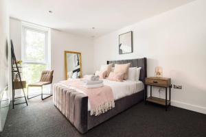 Convenient - ExCel London - O2- 3 Bedroom Apartment في لندن: غرفة نوم بيضاء بسرير كبير وكرسي