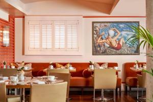 ein Restaurant mit Tischen und einem Gemälde an der Wand in der Unterkunft The Bloomsbury Hotel in London