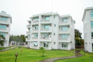 a white building with a grassy yard in front of it at Kijani Suites in Malindi