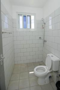 a white bathroom with a toilet and a window at Kijani Suites in Malindi