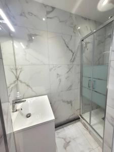 y baño blanco con lavabo y ducha. en Appartement JO proche Paris,CDG,Expo, Stade de France, en Aulnay-sous-Bois