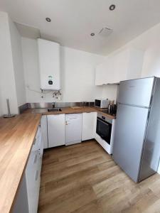 cocina blanca con electrodomésticos blancos y suelo de madera en Appartement JO proche Paris,CDG,Expo, Stade de France, en Aulnay-sous-Bois