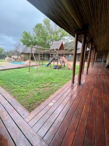 a wooden deck with a playground in the background at Eids Farm in Mmukubyane
