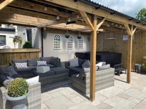 a patio with couches and a piano under a pergola at The Grousemoor - North Wales luxury 7 bedroom holiday rental in Llandegla