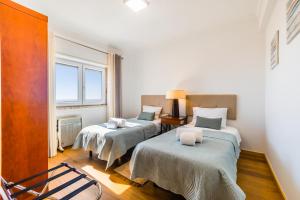 埃里塞拉的住宿－Ericeira Vista Mar Peace and Sea，客房设有两张床和窗户。