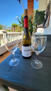 a bottle of wine and two wine glasses on a table at La Casita Denia, charming 2BR Townhouse with shared Pool, 1km to Beach in Els Poblets +30 photos
