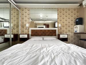 - une chambre avec un grand lit blanc et des miroirs dans l'établissement Bassura Apartment by Aok Property, à Jakarta